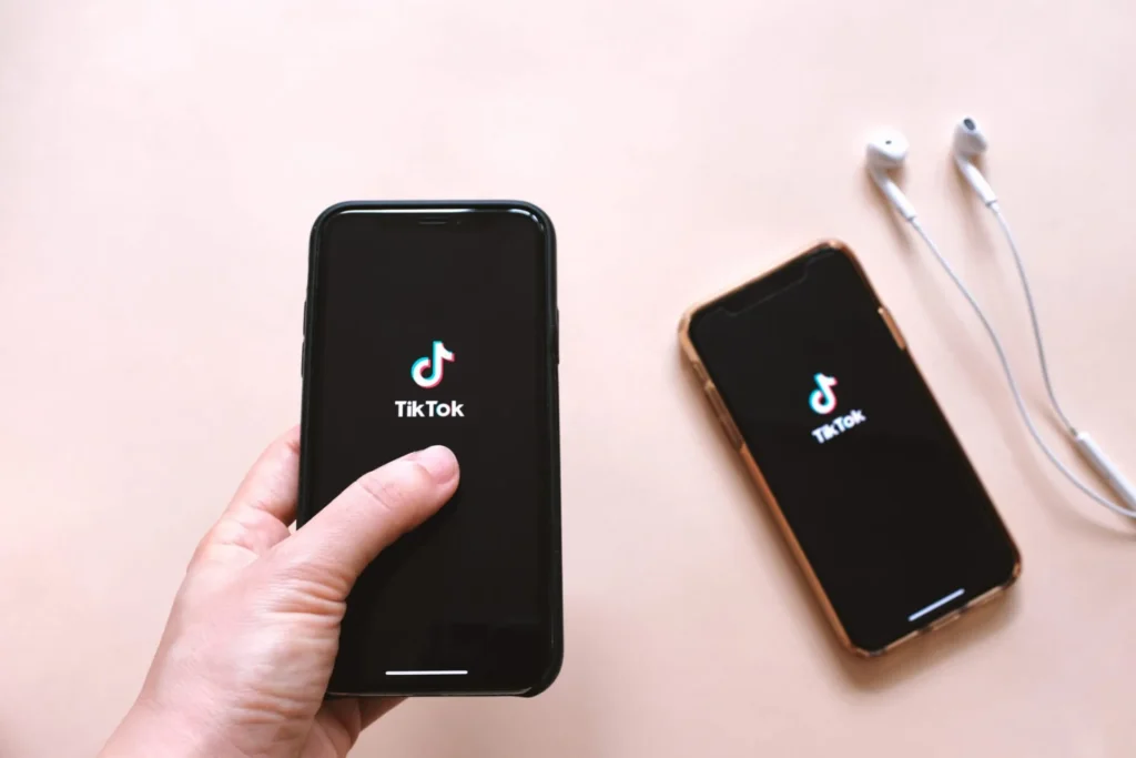 Pessoa com dois celulares abertos no aplicativo do Tiktok