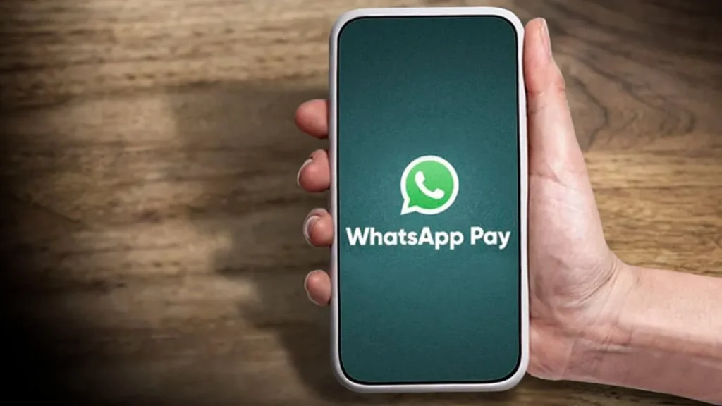 Pessoa segurando celular com nome Whatsapp Pay escrito na tela