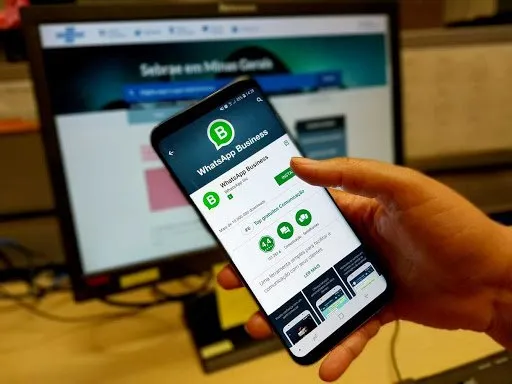 Pessoa segurando celular com tela aberta no aplicativo do WhatsApp Business