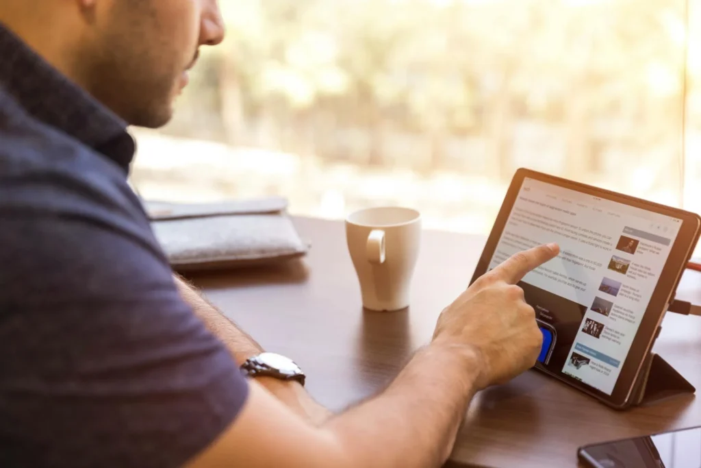 Homem analisando textos do site no tablet para melhorá-los e aumentar a taxa de conversão